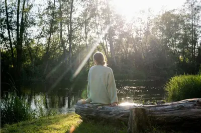 a woman sitting on a log near a lake at Rest Green in Degesiai