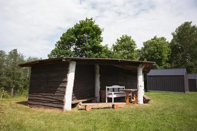 a wooden shed with a bench and a table in a field at Rest Green in Degesiai