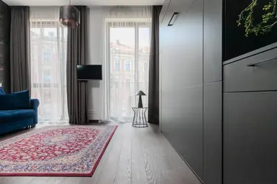 a living room with a blue couch and a large window at Vilnius Old Town Renessainse Studio 3 in Vilnius