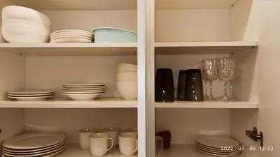 a white cabinet filled with plates and dishes at HaPPy Inn Egle, Self Check-In-24-7, A-C, Parking-in-the-underground-Garage in Vilnius