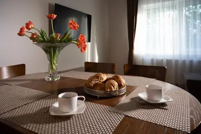 a table with two cups and a bowl of croissants and a vase at Villa ACACIA in Kaunas