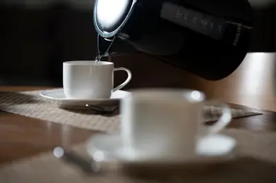 a coffee maker pouring coffee into a cup on a table at Villa ACACIA in Kaunas