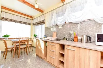 a kitchen with wooden cabinets and a table with chairs at Žemyna Apartmentai in Druskininkai