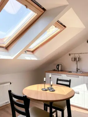 a kitchen and dining room with a wooden table and skylights at Upės apartamentai in Birštonas