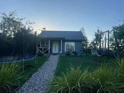 a small white house with a gravel yard at Cozy holiday house with sauna and entertainment in Puskelniai