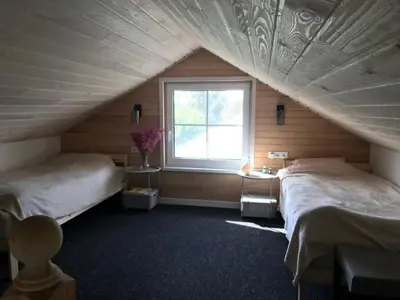 a attic bedroom with two beds and a window at Cozy holiday house with sauna and entertainment in Puskelniai