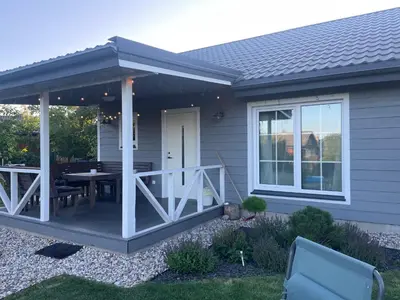 a screened in porch with a table on a deck at Cozy holiday house with sauna and entertainment in Puskelniai