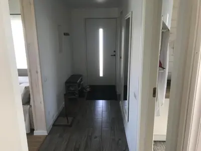 a hallway with a white door and a wooden floor at Cozy holiday house with sauna and entertainment in Puskelniai