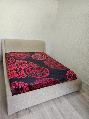 a bed with a black and red blanket on it at Ežero 8-90 in Šiauliai