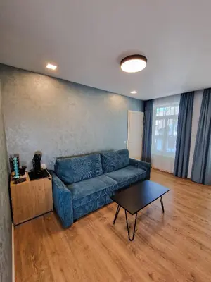 a living room with a blue couch and a table at Editos apartamentai in Jurbarkas