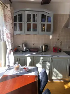 a kitchen with white cabinets and a table in it at Tranquil country cottage with outdoor fireplace in Stelmužė