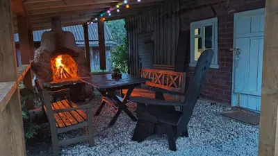 a patio with a fireplace and a table and a chair at Tranquil country cottage with outdoor fireplace in Stelmužė