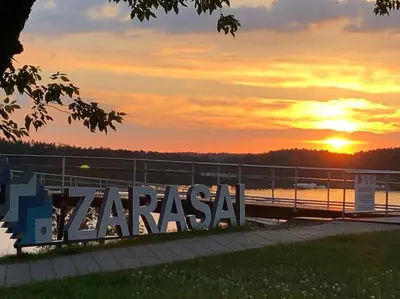 a sign with the sunset in the background at Tranquil country cottage with outdoor fireplace in Stelmužė