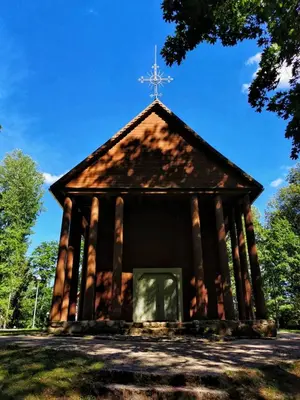 a small chapel with a cross on the roof at Tranquil country cottage with outdoor fireplace in Stelmužė