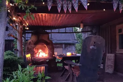 a patio with a grill and a table and a fire place at Tranquil country cottage with outdoor fireplace in Stelmužė