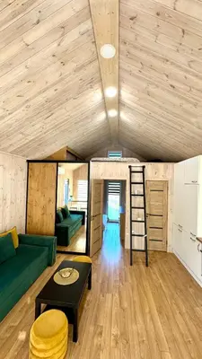 a living room with a green couch and a ladder at Chill House in Anykščiai