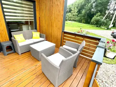 a patio with wicker chairs and tables on a deck at Chill House in Anykščiai