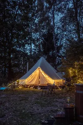 a large tent with chairs in a field at night at Glamping in - luxury tent in Šunupis