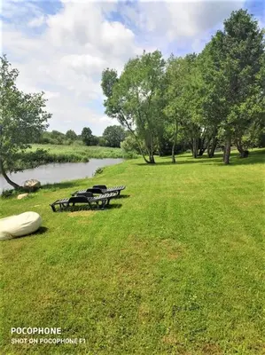 a group of picnic tables in the grass near a lake at Domo Vila in Druskininkai