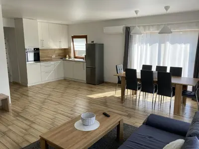 a living room and kitchen with a table and chairs at Domo Vila in Druskininkai