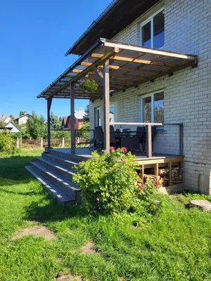 a deck with a pergola on the side of a house at Namas su terasa in Vilnius