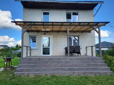 a house with a deck with a table and chairs at Namas su terasa in Vilnius