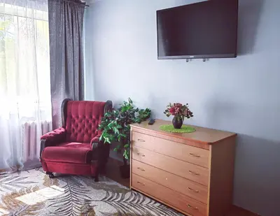 a living room with a red chair and a dresser at Krymo g. Lovely 2 room flat in Šiauliai, near Akropolis in Šiauliai