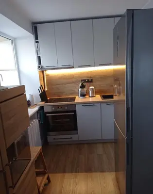 a kitchen with white cabinets and a stainless steel refrigerator at TIMO butas in Druskininkai