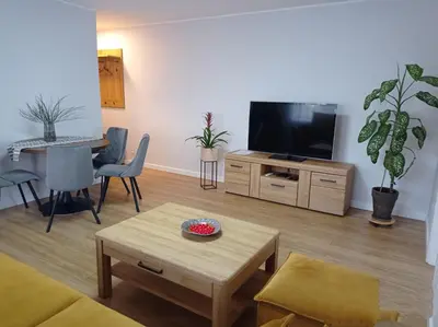 a living room with a flat screen tv and a table at TIMO butas in Druskininkai
