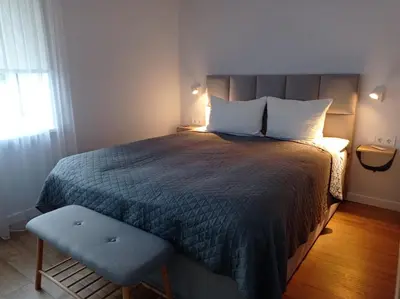 a bedroom with a bed and a chair and a window at TIMO butas in Druskininkai