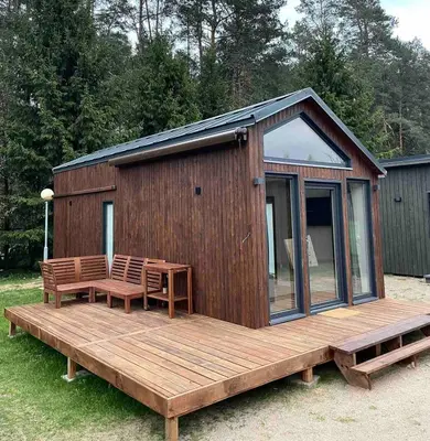 a wooden cabin with a table and benches on a deck at Palūšės Kempingas (nameliai) in Palūšė