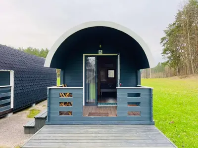 a blue building with a door in a field at Palūšės Kempingas (nameliai) in Palūšė