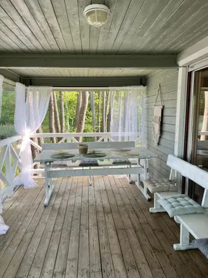 a screened in porch with a table and benches at Kumpuolis LakeHouse in Degučiai