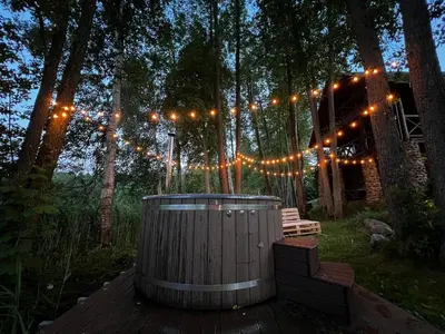 a hot tub in the middle of a forest with lights at Kumpuolis LakeHouse in Degučiai