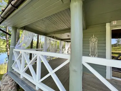 a porch of a wooden house with a chandelier at Kumpuolis LakeHouse in Degučiai