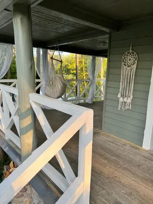 a porch with a white fence and chandelier at Kumpuolis LakeHouse in Degučiai