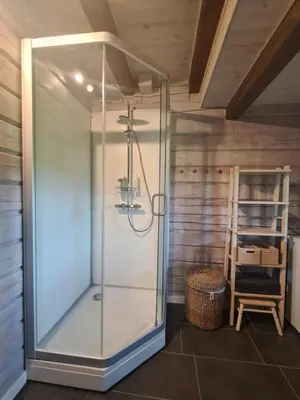 a glass shower in a room with a chair at Rubikių Meldynas Anykščiai in Anykščiai