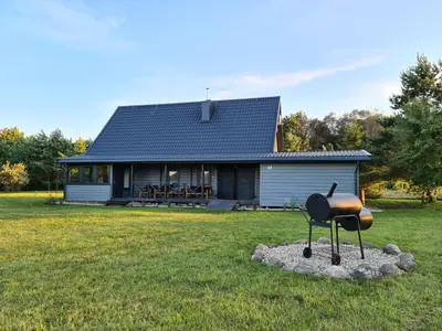 a barbecue grill in front of a house at Rubikių Meldynas Anykščiai in Anykščiai