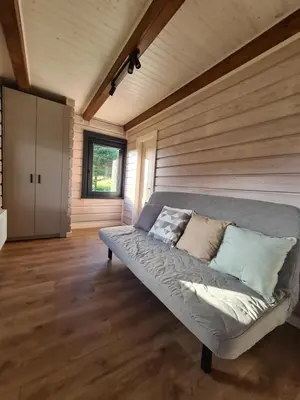 a large couch in a room with wooden walls at Rubikių Meldynas Anykščiai in Anykščiai