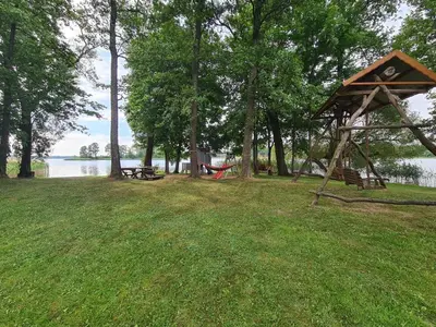 a gazebo in the grass next to a lake at Rubikių Meldynas Anykščiai in Anykščiai