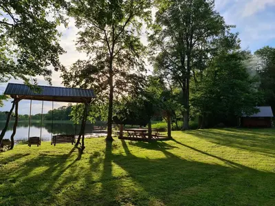 a park with benches and a gazebo next to a lake at Rubikių Meldynas Anykščiai in Anykščiai