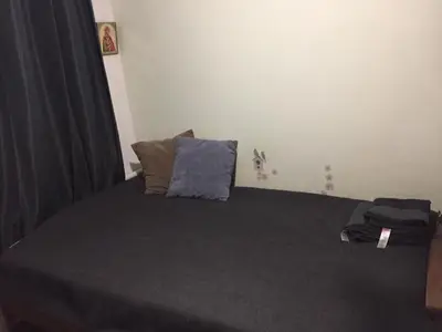 a bedroom with a bed with gray sheets and pillows at Studija virš cukrainės Druskininkuose in Druskininkai