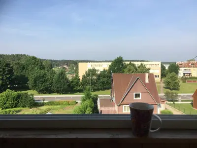a cup of coffee sitting on a window sill at Jaukus būstas netoli Šaulio skulptūros in Druskininkai