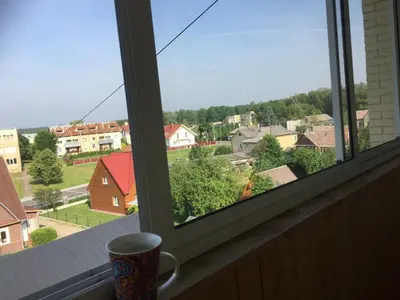 a cup on a window sill with a view of a town at Jaukus būstas netoli Šaulio skulptūros in Druskininkai