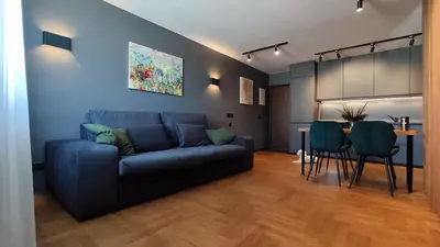 a living room with a blue couch and a table at Dabintos Apartament Druskininkai in Druskininkai