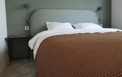 a large bed with a brown blanket and white pillows at Hill Top apartment in central Kedainiai in Kėdainiai
