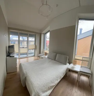 a bedroom with a large white bed and large windows at Apartamentai Muziejaus g. in Birštonas
