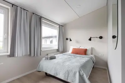 a white bedroom with a bed and a window at Youston self check-in coliving Vilnius in Vilnius