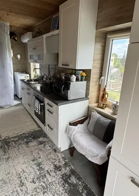 a kitchen with white cabinets and a sink and a window at Dvi liepos in Merkinė