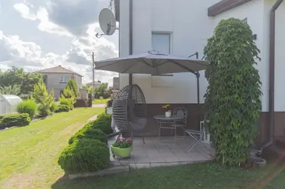 a patio with a table and an umbrella at Dvi liepos in Merkinė